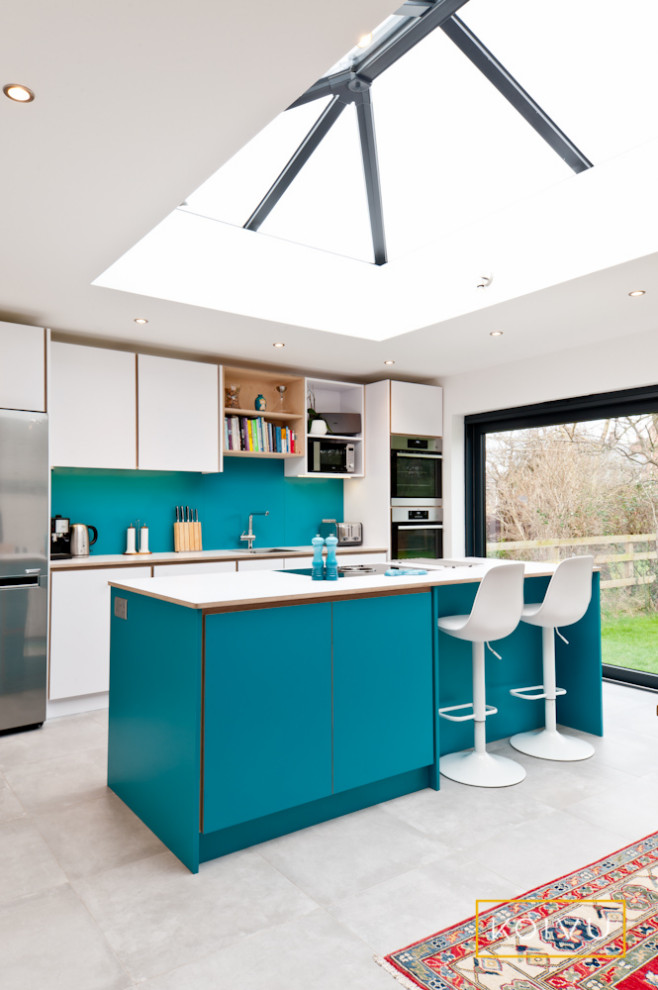 Inspiration for a medium sized contemporary single-wall kitchen/diner in Wiltshire with flat-panel cabinets, turquoise cabinets, laminate countertops, blue splashback, porcelain flooring, an island, grey floors, white worktops, a submerged sink and stainless steel appliances.