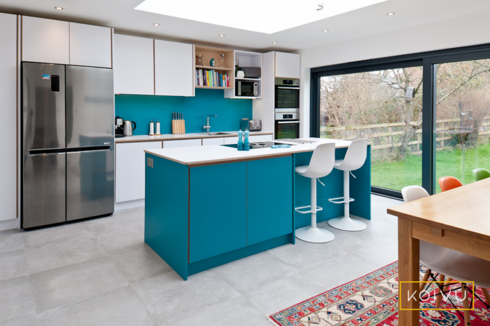 Foto di una cucina minimal di medie dimensioni con ante lisce, ante turchesi, top in laminato, paraspruzzi blu, elettrodomestici da incasso, pavimento in gres porcellanato, pavimento grigio e top bianco