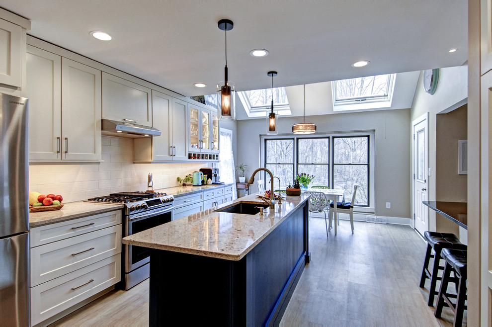 Eat-in kitchen - mid-sized contemporary galley vinyl floor eat-in kitchen idea in Philadelphia with an undermount sink, shaker cabinets, white cabinets, white backsplash, porcelain backsplash, stainless steel appliances, an island, beige countertops and quartz countertops