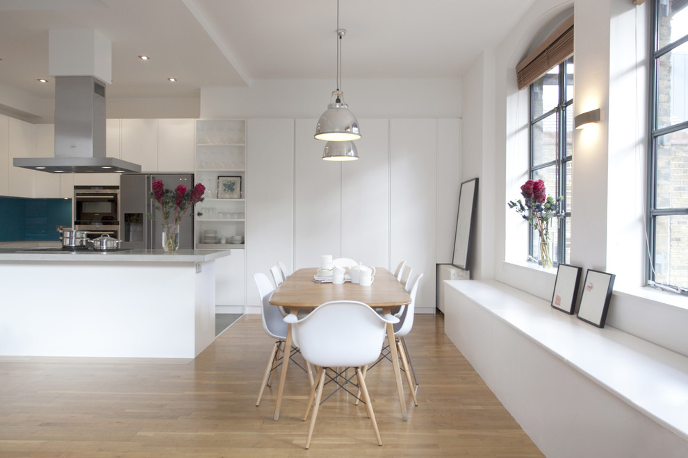 Foto på ett funkis kök och matrum, med rostfria vitvaror, öppna hyllor, vita skåp och blått stänkskydd