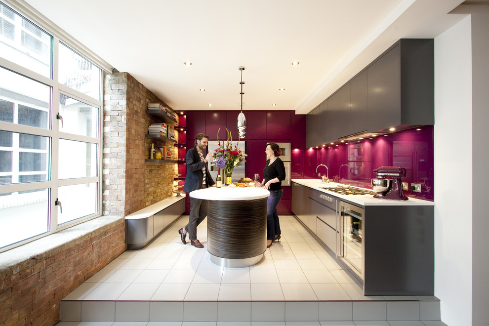 Cette image montre une cuisine grise et rose design en L fermée avec un placard à porte plane, des portes de placard grises, une crédence rose et un électroménager en acier inoxydable.