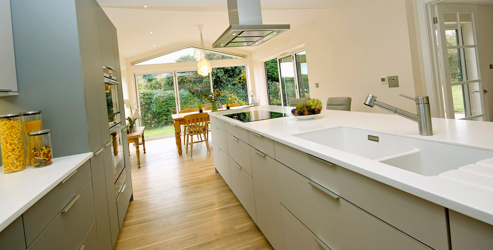 Zweizeilige, Große Moderne Wohnküche mit integriertem Waschbecken, Glasrückwand, schwarzen Elektrogeräten und Kücheninsel in Oxfordshire