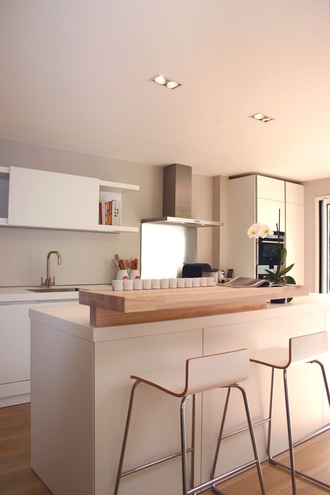 This is an example of a contemporary galley kitchen in London with shaker cabinets and white cabinets.
