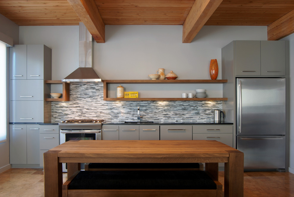 Exempel på ett modernt linjärt kök med öppen planlösning, med en undermonterad diskho, släta luckor, grå skåp, granitbänkskiva, grått stänkskydd, stänkskydd i stickkakel och rostfria vitvaror