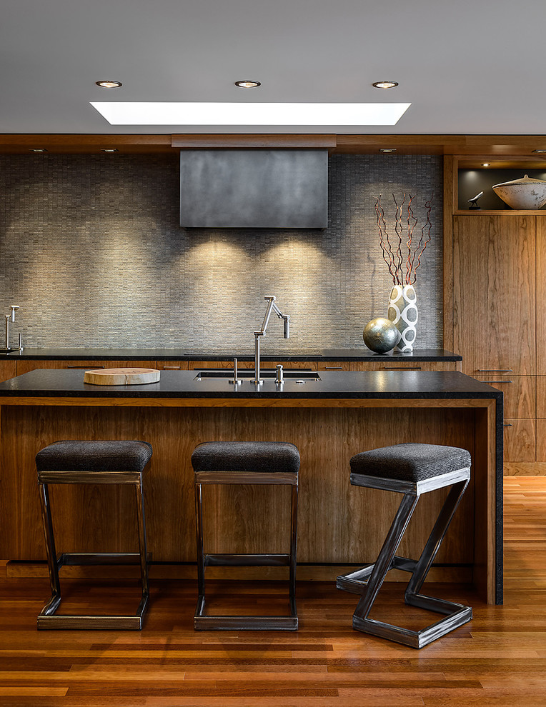 Esempio di una cucina a L minimal con lavello sottopiano, ante lisce, ante in legno bruno e paraspruzzi grigio
