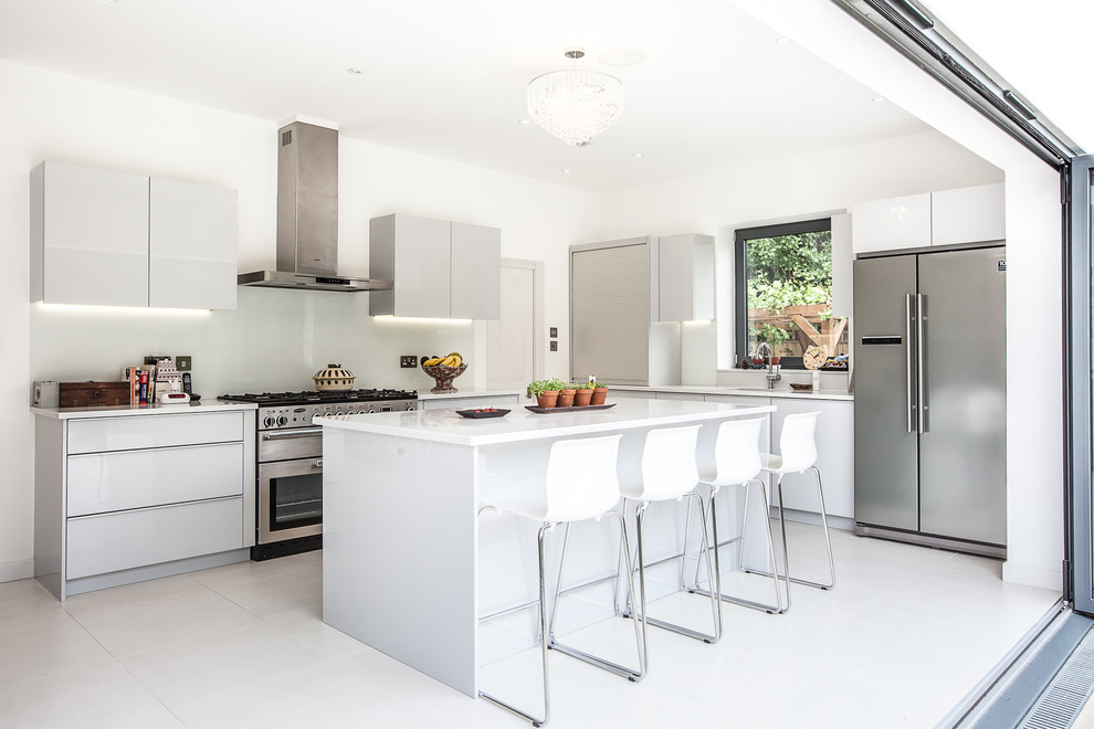 Moderne Küche mit Doppelwaschbecken, flächenbündigen Schrankfronten, weißen Schränken, Küchenrückwand in Weiß und Küchengeräten aus Edelstahl in London