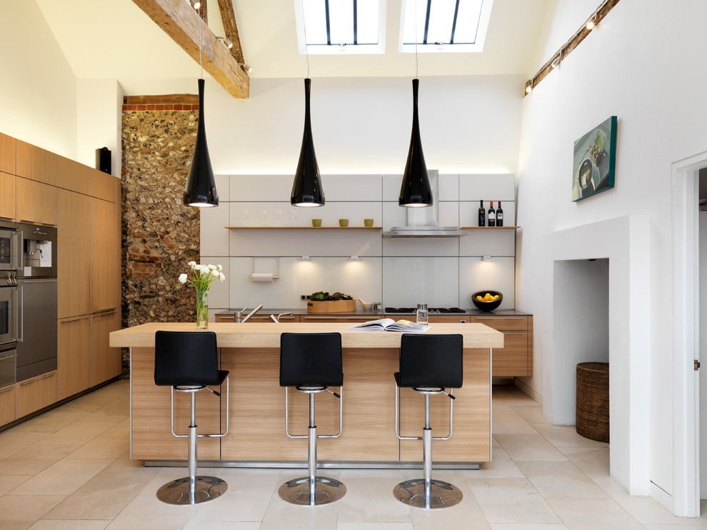 Moderne Küche in U-Form mit flächenbündigen Schrankfronten, hellen Holzschränken, Arbeitsplatte aus Holz, Küchenrückwand in Weiß und Küchengeräten aus Edelstahl in Sonstige