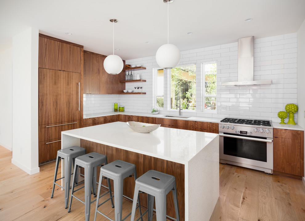 Inspiration for a contemporary l-shaped light wood floor and brown floor kitchen remodel in DC Metro with an undermount sink, flat-panel cabinets, medium tone wood cabinets, white backsplash, subway tile backsplash, paneled appliances, an island and white countertops