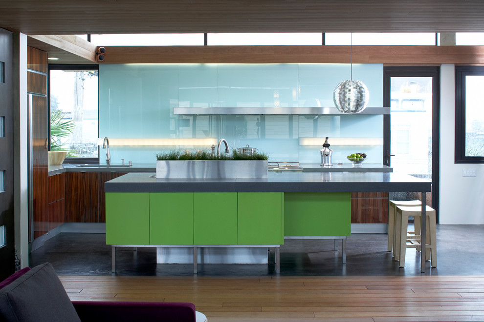 Стильный дизайн: угловая кухня в современном стиле с обеденным столом, врезной мойкой, плоскими фасадами, темными деревянными фасадами, столешницей из бетона, синим фартуком, фартуком из стекла и техникой из нержавеющей стали - последний тренд