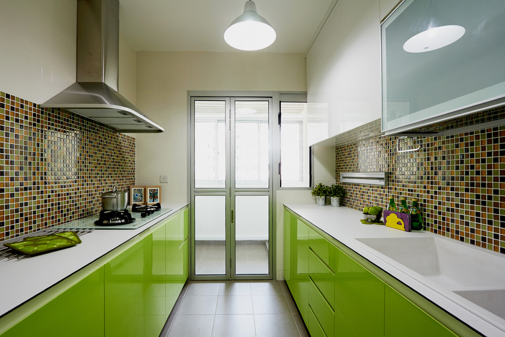 Стильный дизайн: параллельная кухня в современном стиле с монолитной мойкой, плоскими фасадами, зелеными фасадами, разноцветным фартуком и фартуком из плитки мозаики без острова - последний тренд