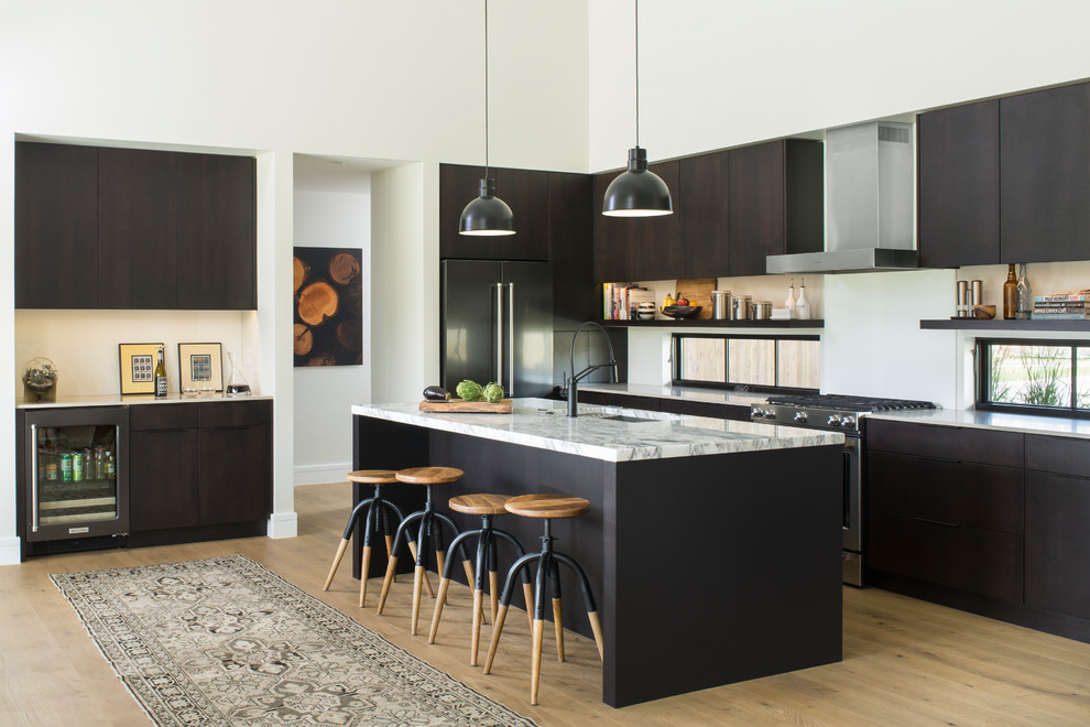 Moderne Küche in L-Form mit Unterbauwaschbecken, flächenbündigen Schrankfronten, Küchengeräten aus Edelstahl, braunem Holzboden, Kücheninsel und braunem Boden in Denver