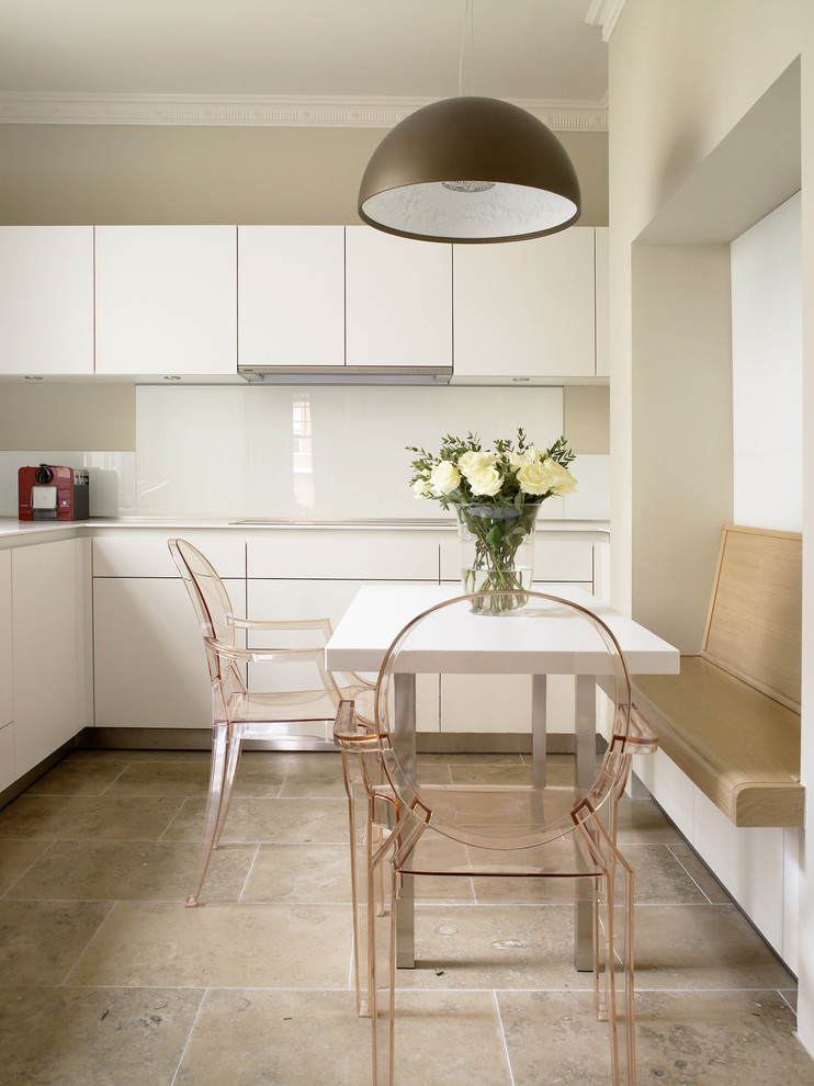 Moderne Wohnküche mit flächenbündigen Schrankfronten, weißen Schränken, Küchenrückwand in Weiß, Glasrückwand, Travertin und beigem Boden in London