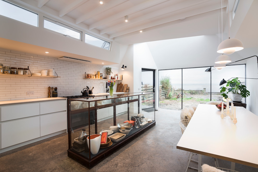 Foto di una grande cucina contemporanea con ante lisce, ante bianche, paraspruzzi bianco, pavimento in cemento e struttura in muratura