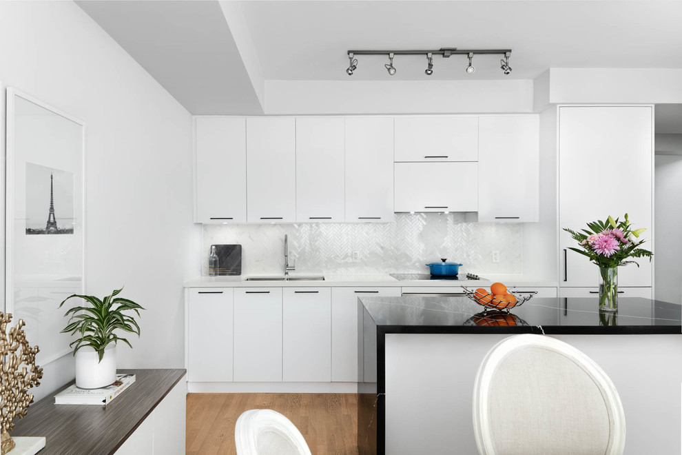Foto di un cucina con isola centrale minimal con lavello a doppia vasca, ante lisce, ante bianche, paraspruzzi bianco, pavimento in legno massello medio e top bianco
