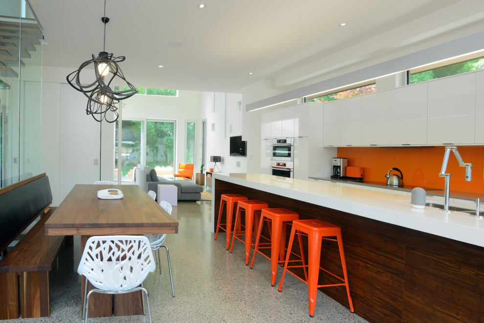 オタワにあるコンテンポラリースタイルのおしゃれなキッチン (フラットパネル扉のキャビネット、白いキャビネット、オレンジのキッチンパネル、パネルと同色の調理設備) の写真