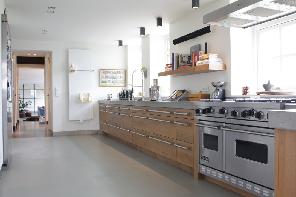Design ideas for a contemporary galley enclosed kitchen in Amsterdam with flat-panel cabinets, medium wood cabinets and stainless steel appliances.