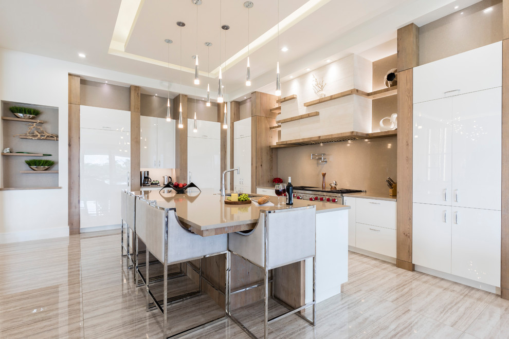 Design ideas for a contemporary l-shaped kitchen in Orlando with a submerged sink, flat-panel cabinets, white cabinets, grey splashback, stone slab splashback, stainless steel appliances, an island, beige floors and grey worktops.