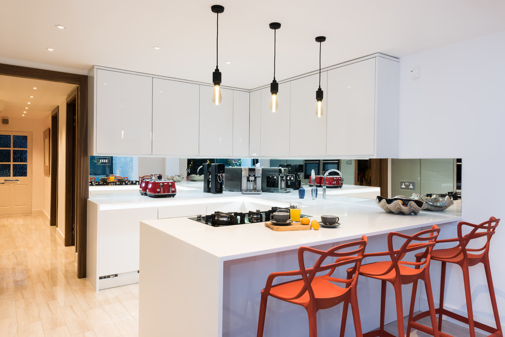 Moderne Küche in U-Form mit integriertem Waschbecken, flächenbündigen Schrankfronten, weißen Schränken, Rückwand aus Spiegelfliesen, schwarzen Elektrogeräten und hellem Holzboden in London