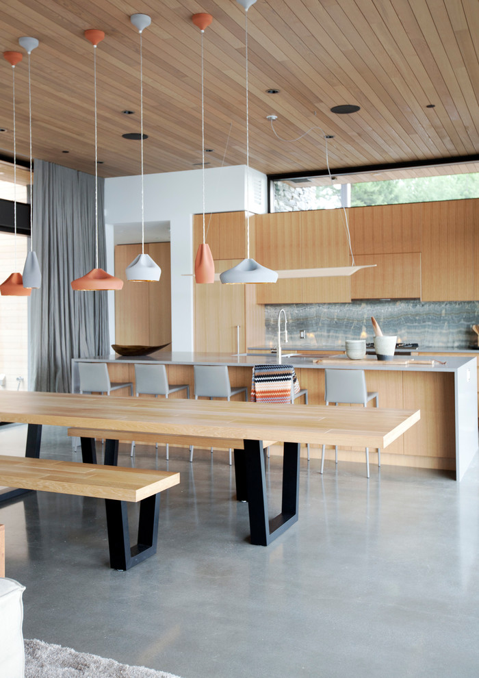 Immagine di una grande cucina minimal con ante lisce, ante in legno chiaro, paraspruzzi grigio, paraspruzzi in lastra di pietra e pavimento in cemento