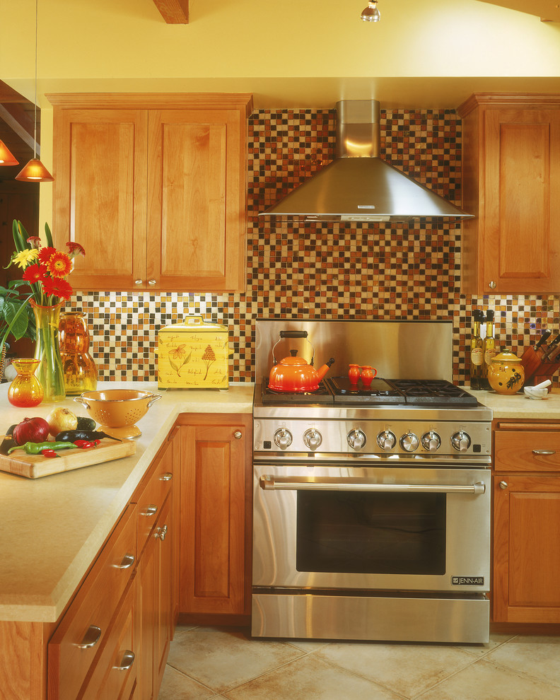Immagine di una cucina contemporanea con elettrodomestici in acciaio inossidabile, ante con bugna sagomata, ante in legno scuro, paraspruzzi marrone e paraspruzzi con piastrelle a mosaico