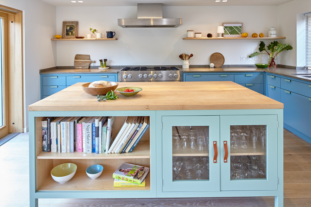 Mittelgroße Moderne Wohnküche mit Unterbauwaschbecken, blauen Schränken, Kalkstein-Arbeitsplatte, Küchengeräten aus Edelstahl, hellem Holzboden und Kücheninsel in Sonstige