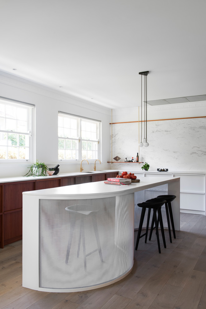 Idéer för ett stort modernt kök, med en undermonterad diskho, luckor med upphöjd panel, vita skåp, bänkskiva i kvarts, vitt stänkskydd, stänkskydd i marmor, svarta vitvaror, ljust trägolv och en köksö