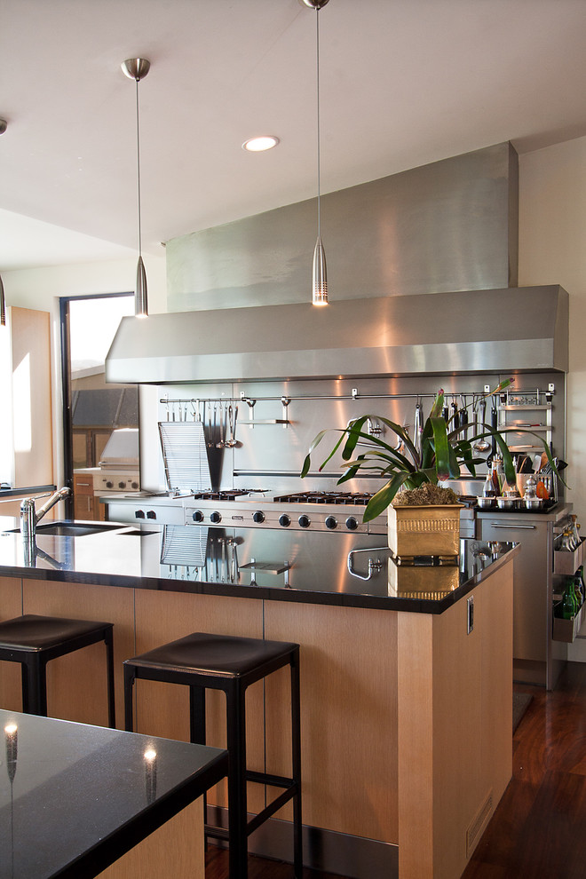 Bild på ett funkis kök, med rostfria vitvaror och stänkskydd med metallisk yta