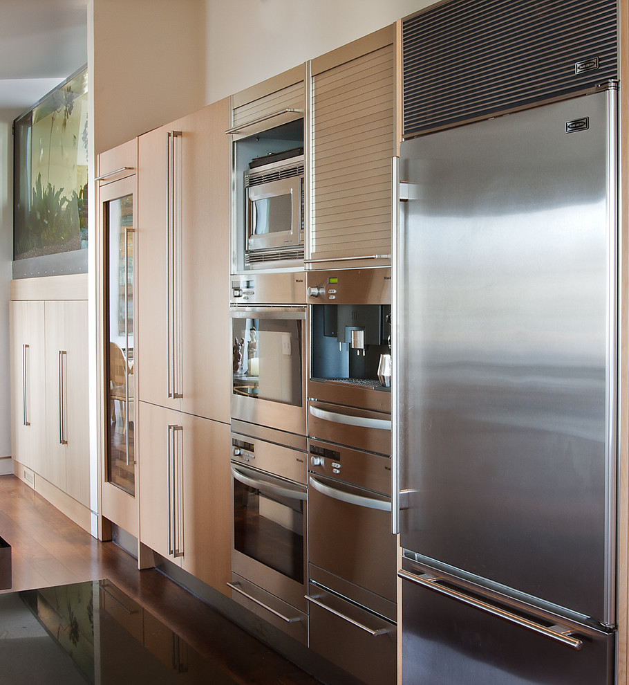 This is an example of a contemporary kitchen in San Francisco with stainless steel appliances, flat-panel cabinets and light wood cabinets.