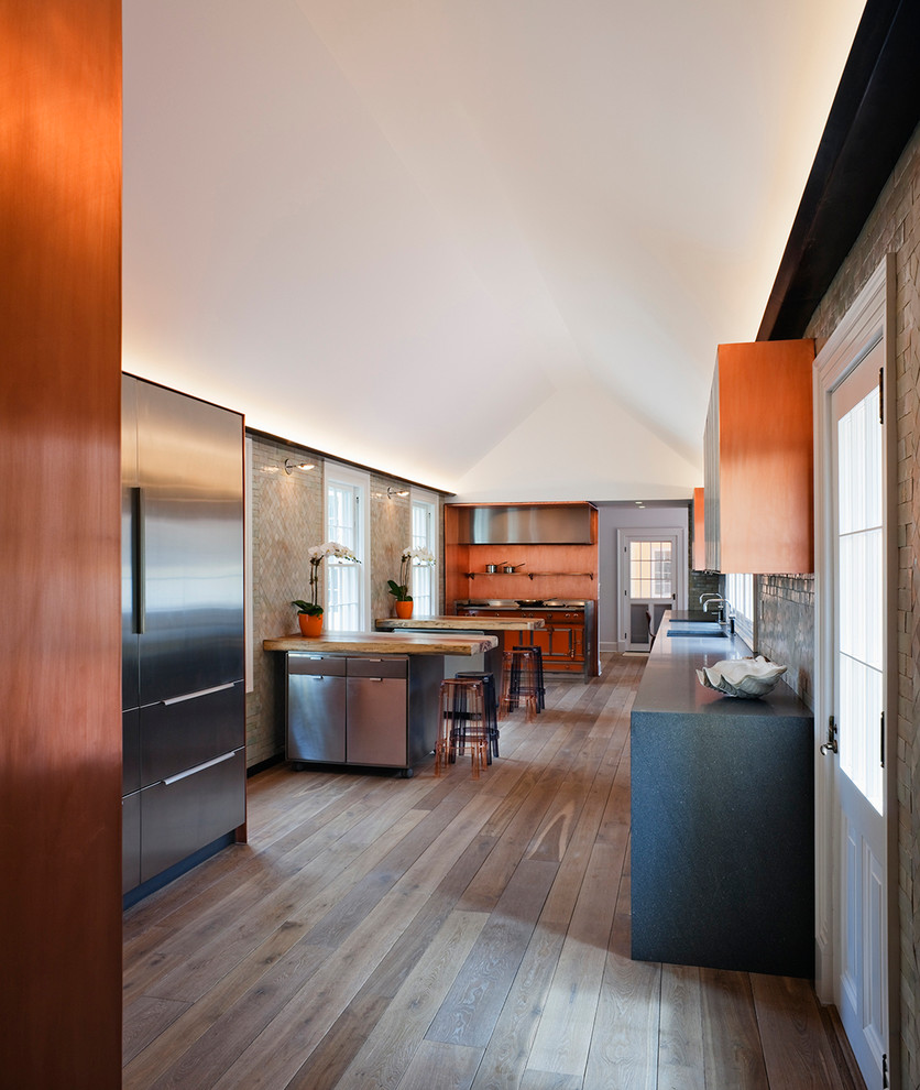 Modelo de cocina alargada contemporánea con salpicadero naranja y electrodomésticos de acero inoxidable