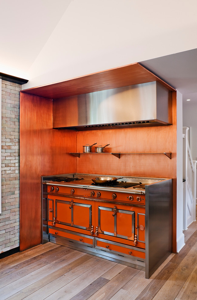 Contemporary kitchen in New York with orange splashback and coloured appliances.