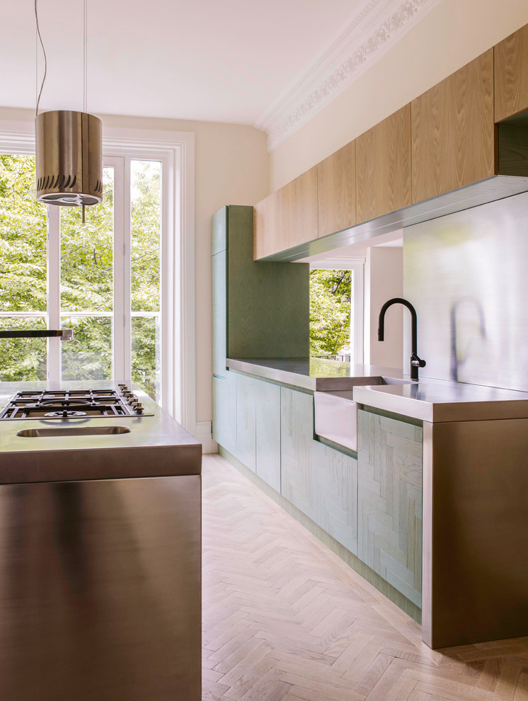 Inspiration for a contemporary kitchen/diner in Other with a belfast sink, turquoise cabinets, stainless steel worktops, metallic splashback, stainless steel appliances, light hardwood flooring and an island.