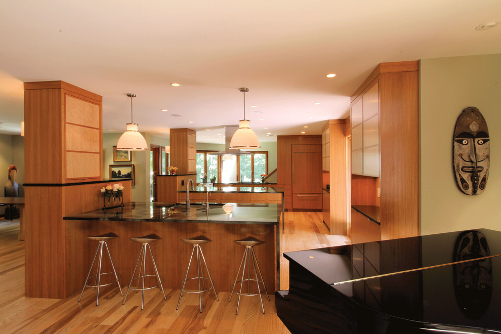 Ejemplo de cocina contemporánea abierta con armarios con paneles lisos, puertas de armario de madera oscura y electrodomésticos con paneles