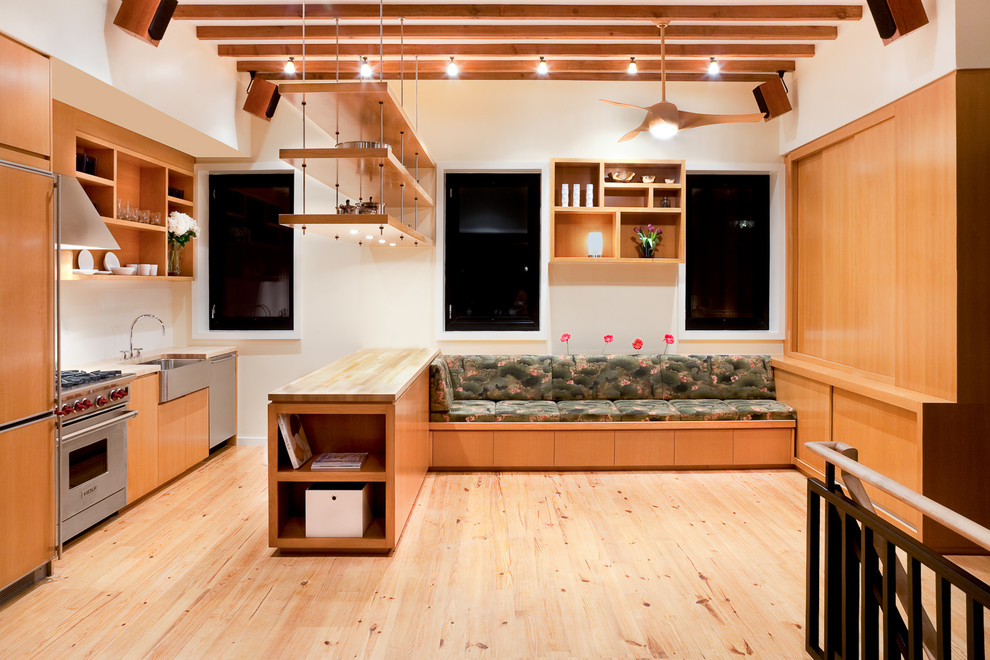 ニューヨークにあるコンテンポラリースタイルのおしゃれなI型キッチン (エプロンフロントシンク、木材カウンター、フラットパネル扉のキャビネット、パネルと同色の調理設備、中間色木目調キャビネット) の写真