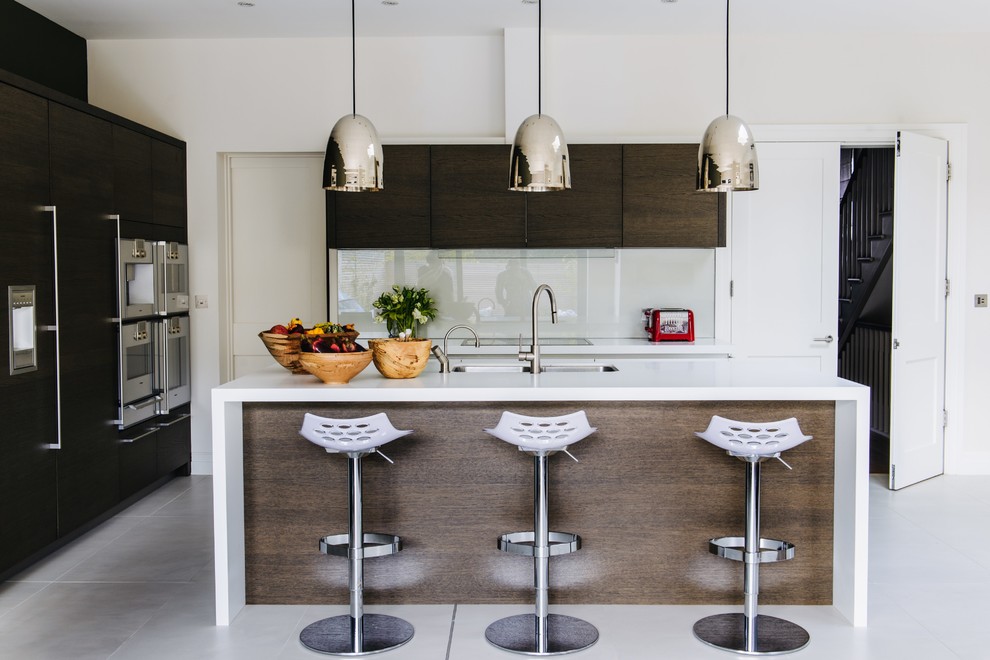 Moderne Küche mit Unterbauwaschbecken, flächenbündigen Schrankfronten, Küchenrückwand in Weiß, Glasrückwand, Küchengeräten aus Edelstahl und Kücheninsel in London