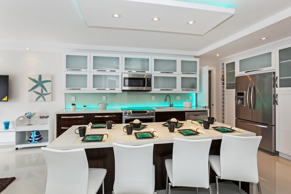 Design ideas for a contemporary l-shaped open plan kitchen in Miami with a single-bowl sink, glass-front cabinets, white cabinets, stainless steel appliances and an island.