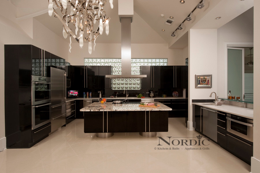 Example of a large trendy u-shaped porcelain tile eat-in kitchen design in New Orleans with an undermount sink, flat-panel cabinets, black cabinets, granite countertops, black backsplash, glass sheet backsplash, stainless steel appliances and an island