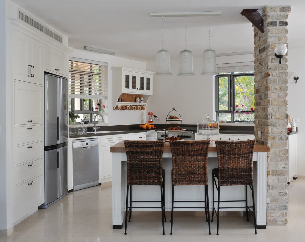 Ejemplo de cocina actual con electrodomésticos de acero inoxidable, fregadero encastrado, armarios estilo shaker, puertas de armario blancas y encimera de madera