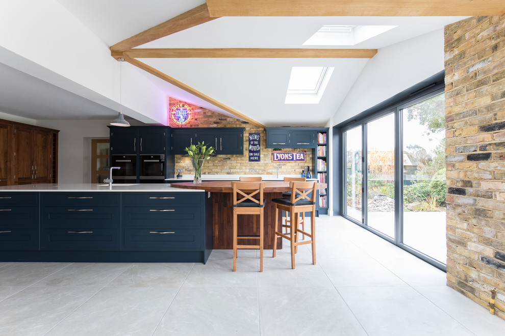 Mittelgroße, Zweizeilige Klassische Küche mit flächenbündigen Schrankfronten, Kücheninsel, grauem Boden und blauen Schränken in Sussex
