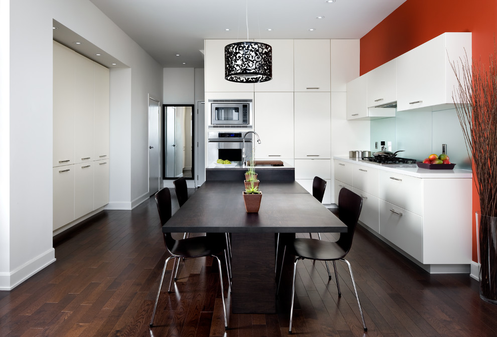 Moderne Wohnküche in L-Form mit flächenbündigen Schrankfronten, weißen Schränken, Küchenrückwand in Blau, Glasrückwand, Küchengeräten aus Edelstahl und dunklem Holzboden in Toronto