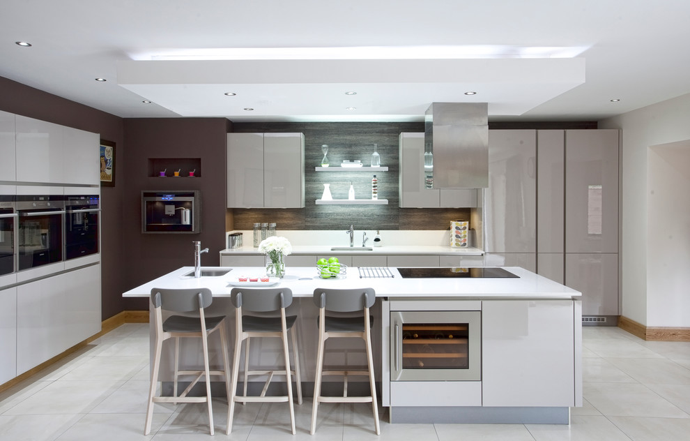 Offene Moderne Küche in L-Form mit Unterbauwaschbecken, flächenbündigen Schrankfronten, grauen Schränken, Küchenrückwand in Weiß und Elektrogeräten mit Frontblende in Belfast