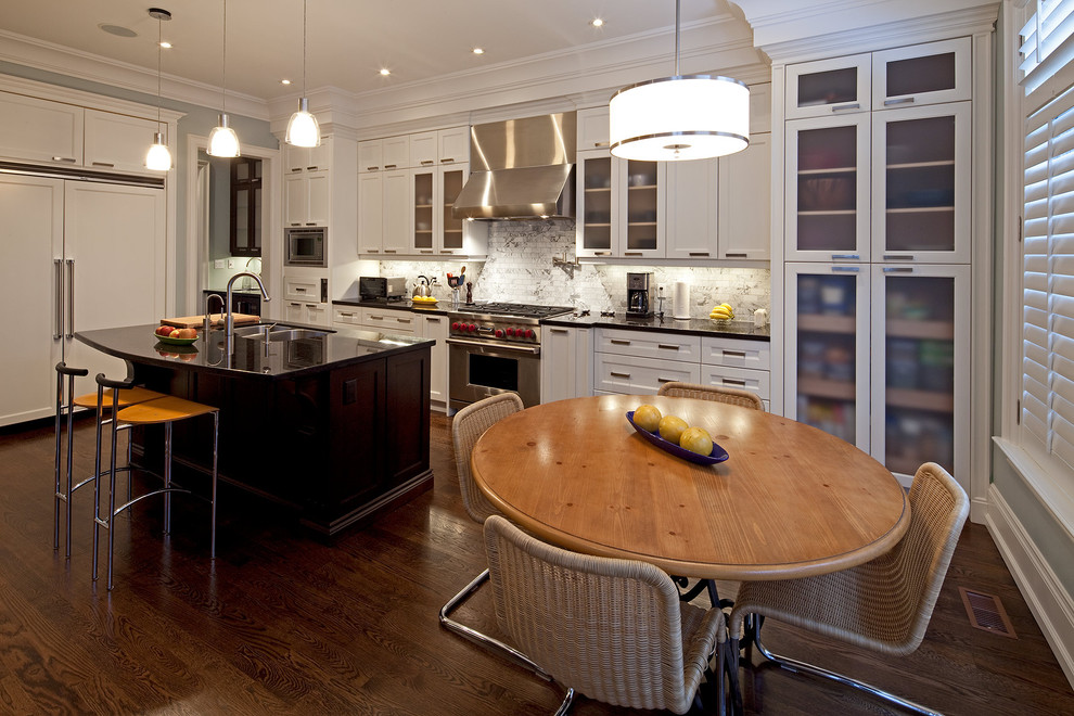 Example of a trendy kitchen design in Toronto with stainless steel appliances, a double-bowl sink, glass-front cabinets, white cabinets, white backsplash and stone tile backsplash