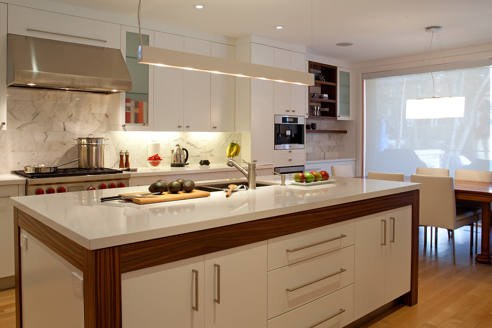 This is an example of a contemporary kitchen/diner in Toronto with stainless steel appliances, a submerged sink, flat-panel cabinets, white cabinets, white splashback and stone tiled splashback.
