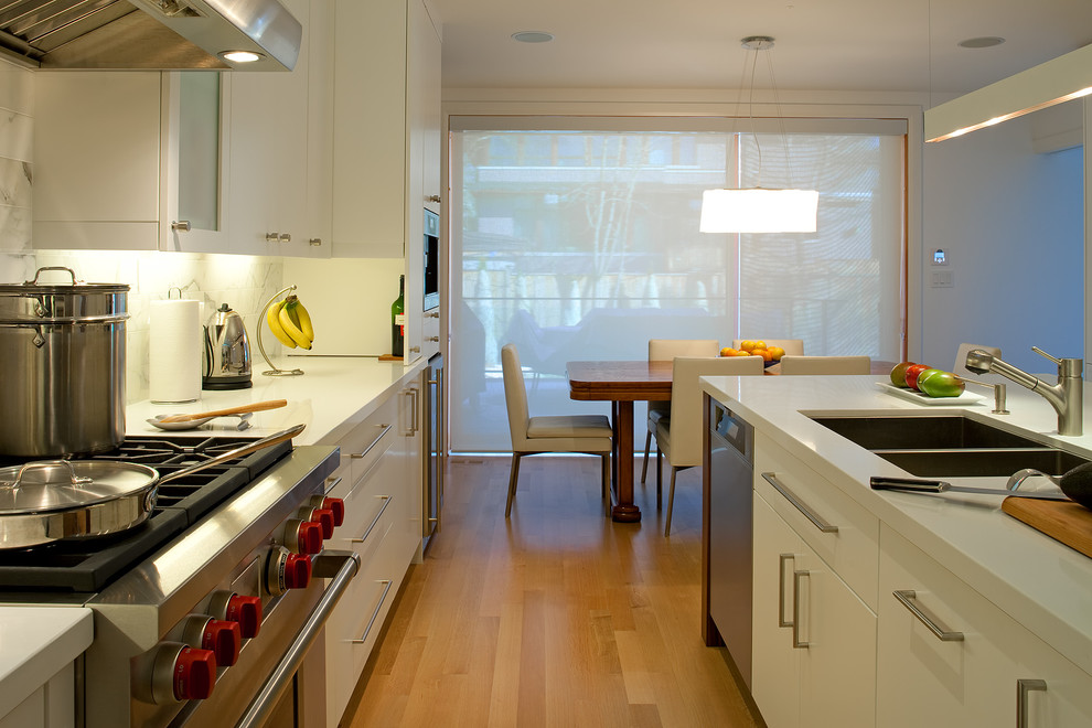 Foto på ett funkis kök och matrum, med rostfria vitvaror, en dubbel diskho, släta luckor och vita skåp