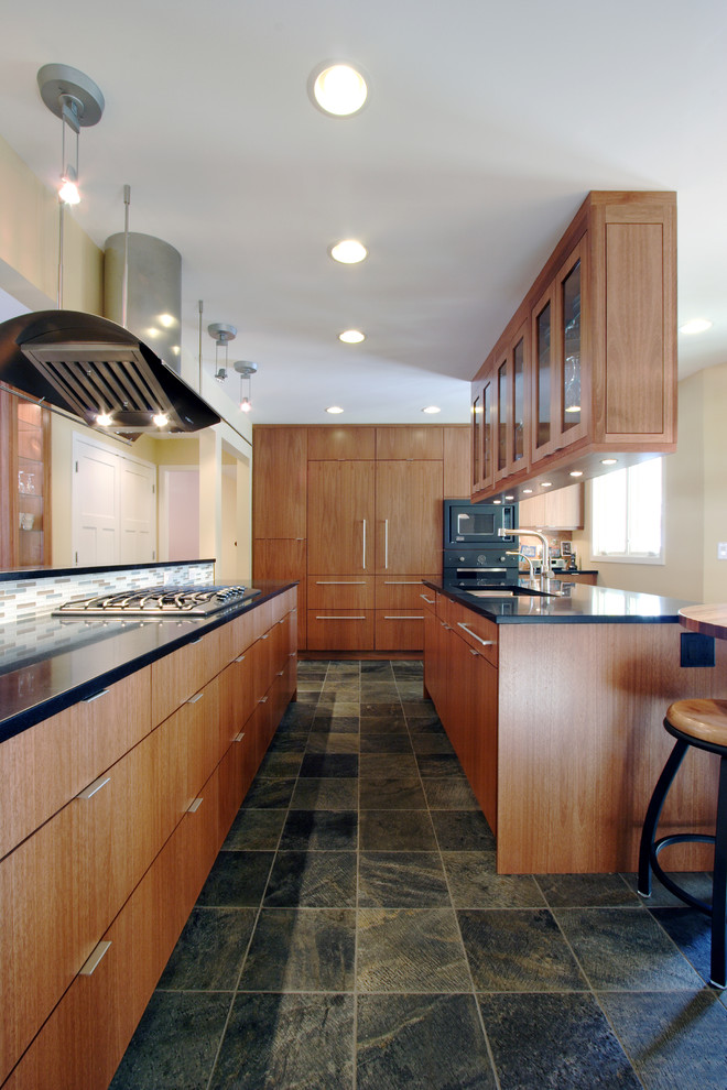ミネアポリスにあるコンテンポラリースタイルのおしゃれな細長いキッチン (フラットパネル扉のキャビネット、中間色木目調キャビネット、ボーダータイルのキッチンパネル、パネルと同色の調理設備) の写真