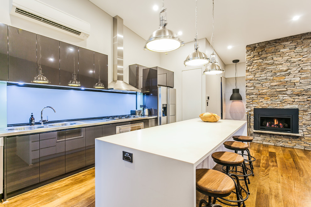Zweizeilige Moderne Küche mit integriertem Waschbecken, flächenbündigen Schrankfronten, grauen Schränken, Edelstahl-Arbeitsplatte, Küchengeräten aus Edelstahl, braunem Holzboden und Kücheninsel in Perth
