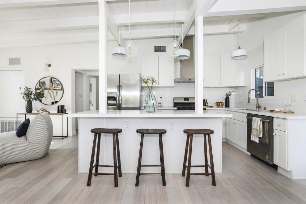 Example of a trendy l-shaped gray floor kitchen design in Los Angeles with an undermount sink, shaker cabinets, white cabinets, stainless steel appliances, an island and white countertops