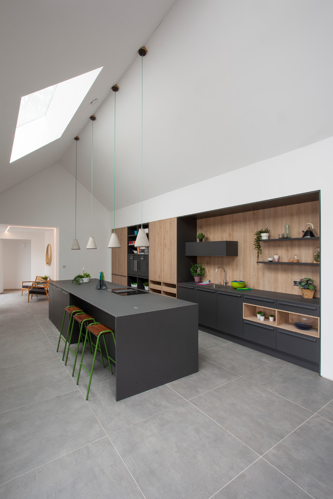 Example of a trendy l-shaped gray floor kitchen design in West Midlands with an undermount sink, flat-panel cabinets, gray cabinets, brown backsplash, wood backsplash, paneled appliances and gray countertops