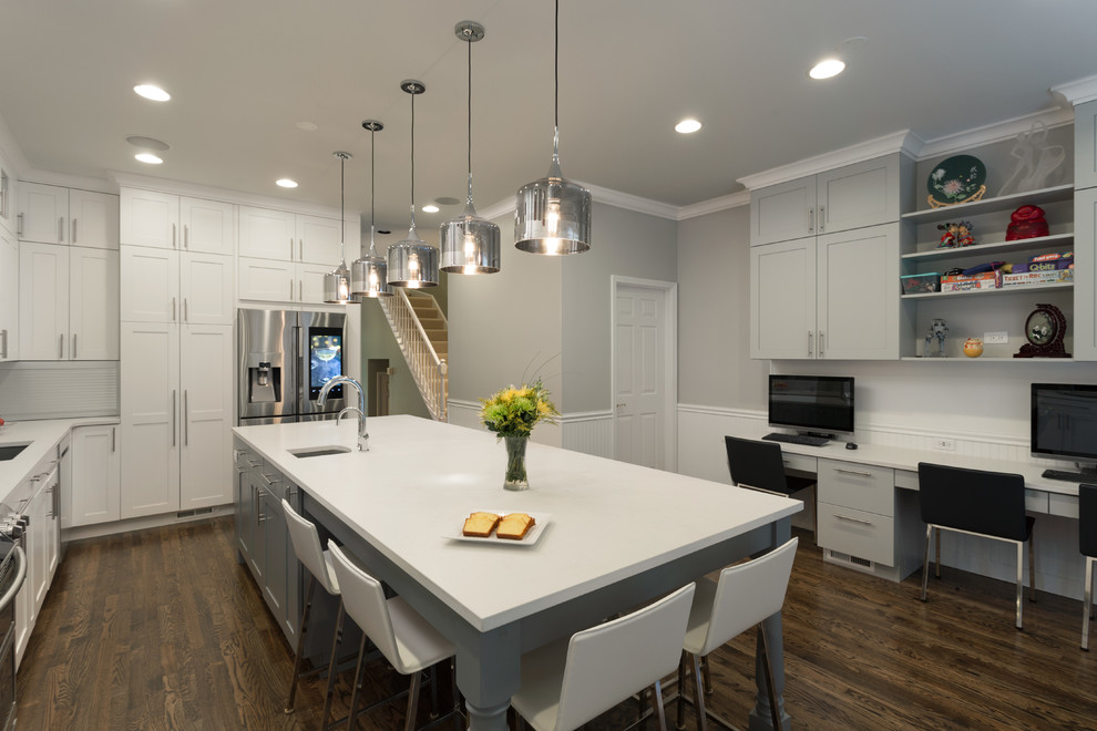This is an example of a medium sized industrial l-shaped open plan kitchen in Chicago with a submerged sink, shaker cabinets, white cabinets, engineered stone countertops, multi-coloured splashback, metro tiled splashback, stainless steel appliances, dark hardwood flooring and an island.