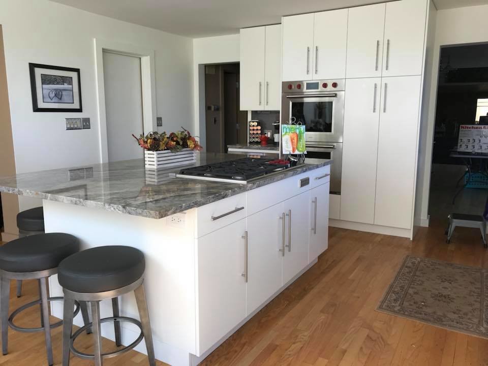 Mid-sized trendy l-shaped light wood floor and brown floor eat-in kitchen photo in New York with an undermount sink, flat-panel cabinets, white cabinets, granite countertops, black backsplash, porcelain backsplash, stainless steel appliances and an island