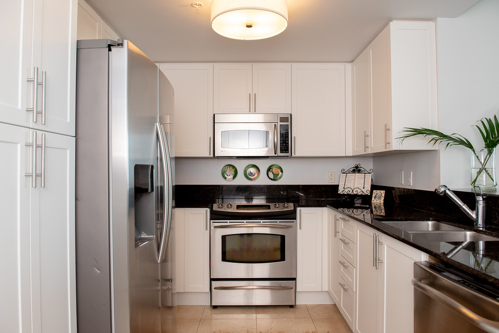 Cette image montre une petite cuisine américaine parallèle design avec un placard à porte shaker et des portes de placard blanches.